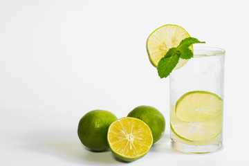 Lemon juice on white  with lemon be side and mint leaves on top in isolated background for healthy...