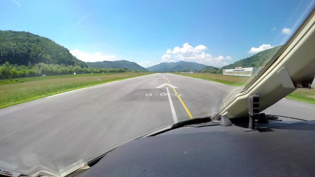 Cockpit view of an aircraft taking off from a lakeside airport in the Swiss Alps on a beautiful, sunny day.