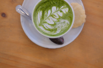 hot matcha green tea with leaves latte art on wood table