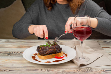 The girl cuts a baked dish of meat on a plate.