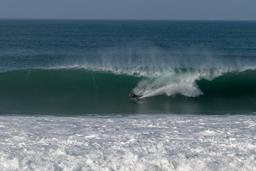 Surfer on Atlantic ocean wave , Nazare , Portugal.