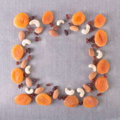 Fototapeta na wymiar Fruit frame of dried apricots, raisins, cashews and almonds. On tablecloth. Place for text. Top view