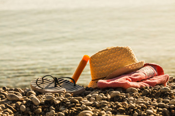 Sun hat and flip flops on stone beach