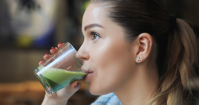 Woman Drinking Matcha Latte In Cafe