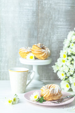 Delicious cake with coconut chips on pink  plate on white table, autumn white chrysanthemum and cup of coffee