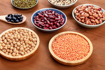 Various legumes on a dark rustic wooden background. Red kidney beans, lentils, chickpeas, soybeans, black peas