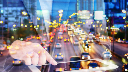 Double exposure businessman touching tablet with Evening traffic,Motion blur and bokeh effect viewed from the road bridge