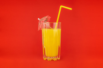 Orange cocktail drink on red background.  Image of citrus juice glass at bright minimalistic environment.