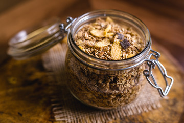 Glass jar with assorted seeds, cereal, oats and dried fruits.