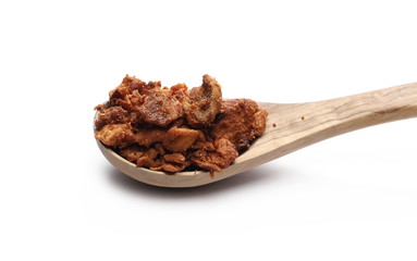 Pork cracklings in wooden spoon isolated on white background