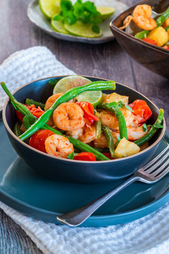 Thai prawns with pineapple and green beans on rustic wooden table