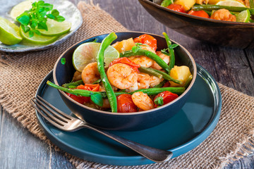 Thai prawns with pineapple and green beans on rustic wooden table