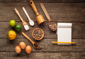 Ingredients for baking - flour, brown sugar, lime, allspice, wooden spoon, rolling pin, eggs. Top view with blank paper for recipe.