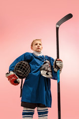 A hockey player in uniform with equipment over pink studio background. The athlete, child, sport,...