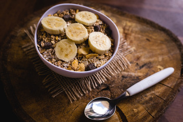 Bowl of cereal with fruit, pieces of banana with oats and cereal.