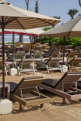 Wooden beach lounge chairs under tents on the tropical beach, perfect idyllic tropical vacation concept
