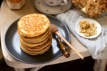 Pancakes with banana, nuts and honey, served with tea. Rustic style.