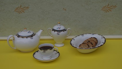 English teacup with saucer, teapot, sugar bowl and a cake bowl with cookies, fine bone china porcelain