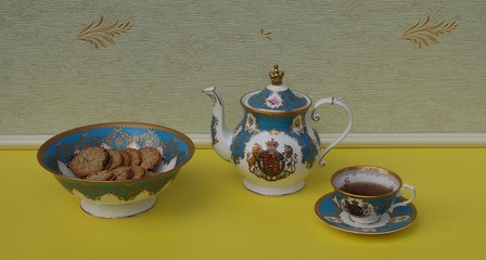 English teacup with saucer, teapot, and a cake bowl with cookies, fine bone china porcelain