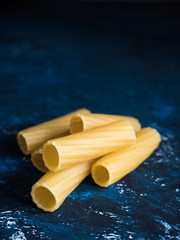 Dry pasta Tortiglioni closeup on a dark blue background. Front view, space for text