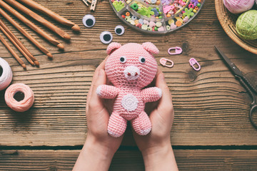 Pink pig. Crochet toy for child. On table threads, needles, hook, cotton yarn. Handmade crafts. DIY concept. Small business. Income from hobby