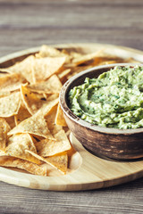 Guacamole with tortilla chips on the wooden tray