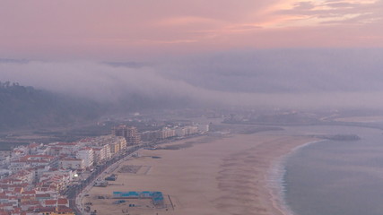 Obraz premium View of Nazare panorama with cabins of Funicular timelapse. Fog coming from ocean at evening during sunset.
