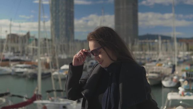 Woman in sunglasses standing with a lot of yachts and boats behind in port . 4k shot