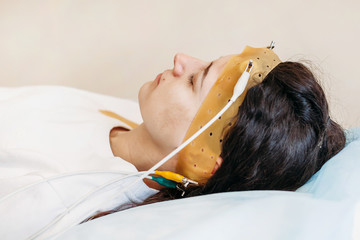 Young woman wearing the brainwave Scanning Headset Sits in a Chair In the Brain Study Laboratory...