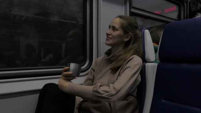 Beautiful young woman holding cup of tea traveling by train