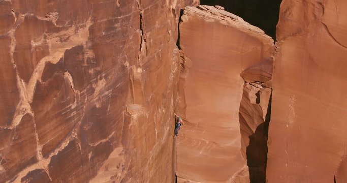 Man rock climbing extreme vertical wall reaching for top 