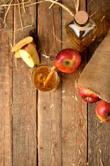 Fototapeta na wymiar Top view of homemade apple juice with ice, red apples, straw, still life on a wooden table - vertical photo