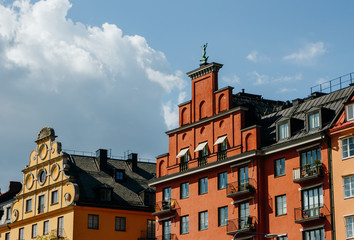 Fototapeta premium Old tiled roofs in district Kungsholmen in Stockholm, Sweden. Side view. Bronze green statues on the tops. Sunny day. Norr Malarstrand street architecture.