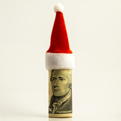 The ten-dollar bill is rolled up and the red Santa Claus hat at the top. New year surprise. Funny portrait of president Hamilton. Financial concept for Christmas decor. White background. Square frame.