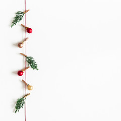 Fototapeta na wymiar Christmas composition. Garland made of red and golden balls, fir tree branches on white background. Christmas, winter, new year concept. Flat lay, top view, copy space, square