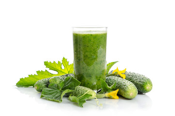  glass with green smoothie and  cucumbers, flowers, leaves isolated on white