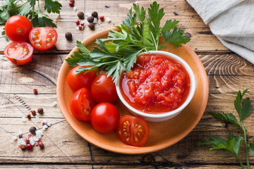 Tomato sauce pasta in a bowl and fresh tomatoes with parsley on a wooden table