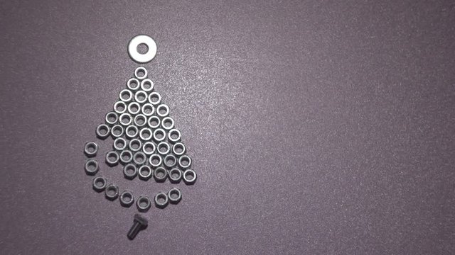 Time Lapse. Iron Christmas tree of bolts and nuts on a plain background