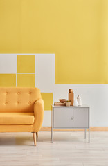 Decorative yellow white wall yellow sofa and grey cabinet. Room interior style.