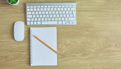 Computer keyboard, mouse and notebook with a pencil on the table