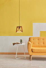 Yellow sofa wooden lamp and coffee table in the yellow wall background.
