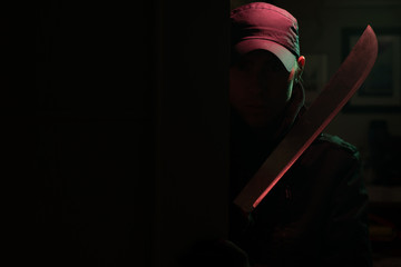 Image of killer with machete in dark apartment with red light - obrazy, fototapety, plakaty