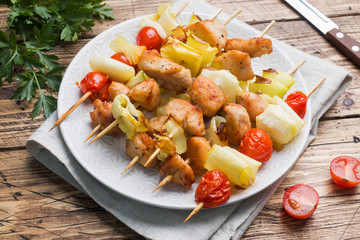 Kebab chicken, zucchini and tomatoes on skewers in a plate. Wooden table.