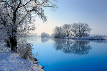 Winter Landscape Reflecting in River, Trees covered by hoarfrost and snow