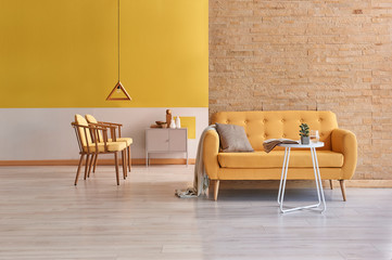 Brick wall yellow sofa close up concept and yellow wall wooden chair and grey cabinet background.