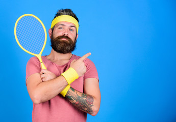 Athlete hold tennis racket in hand on blue background. Tennis sport advertisement. Tennis club concept. Man bearded hipster wear old school sport outfit with bandages. Tennis player retro fashion