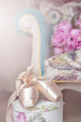 Pink pointes with ribbons and flowers. Spring ballet shoes with roses on the background. Vintage background. Soft light. Copy space