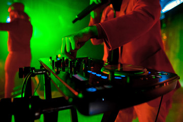 Dj mixes the track in the nightclub at party. In the background laser light show