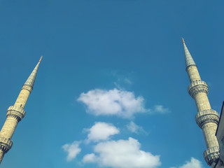 Bottom view Panorama with two minarets of an old mosque against the blue sky. Copy space for...