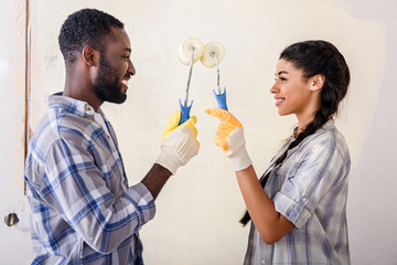side view of couple with rolling brushes looking at each other while making renovation of home